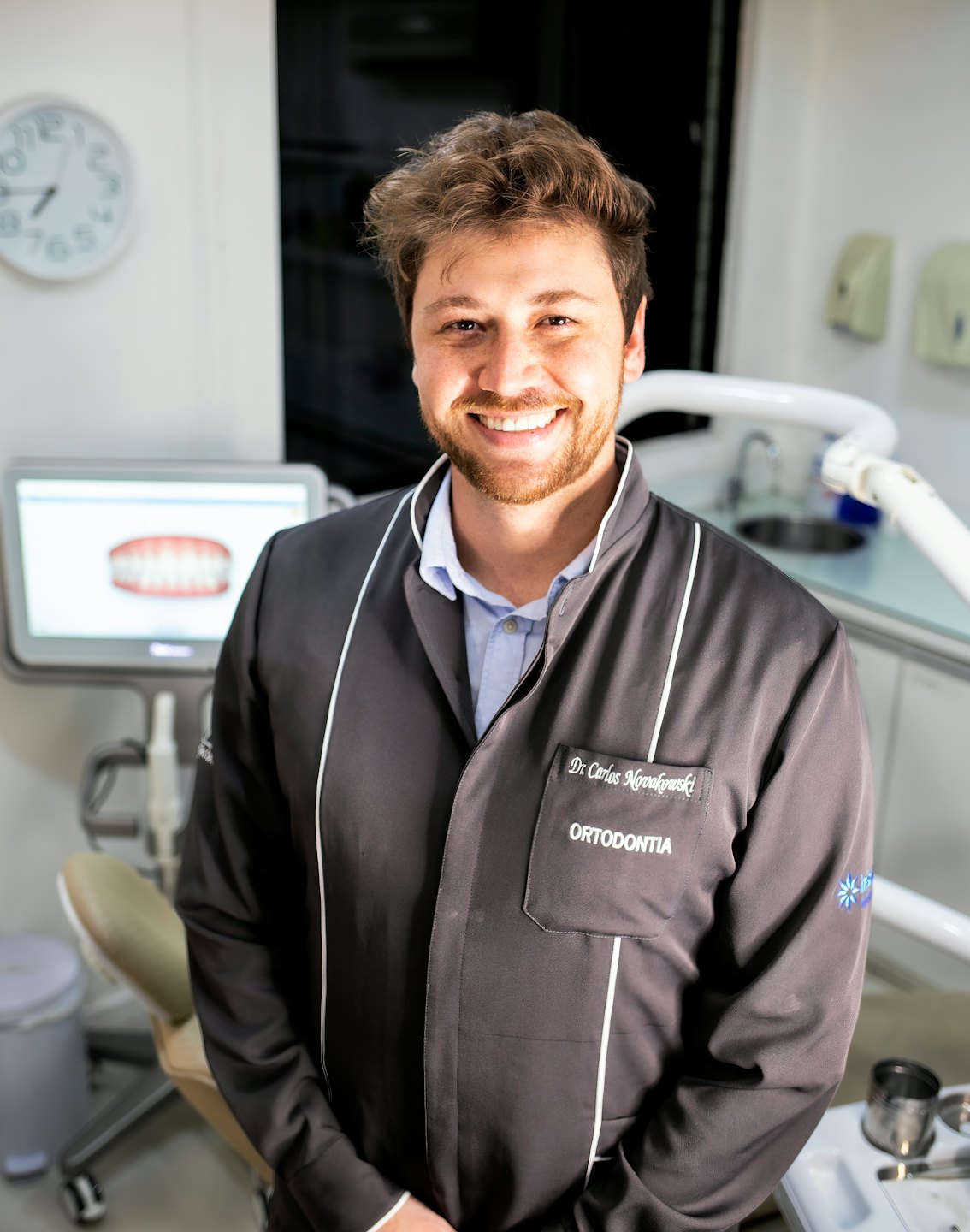 Dentista sonriente en una clínica dental moderna examina un modelo 3D.