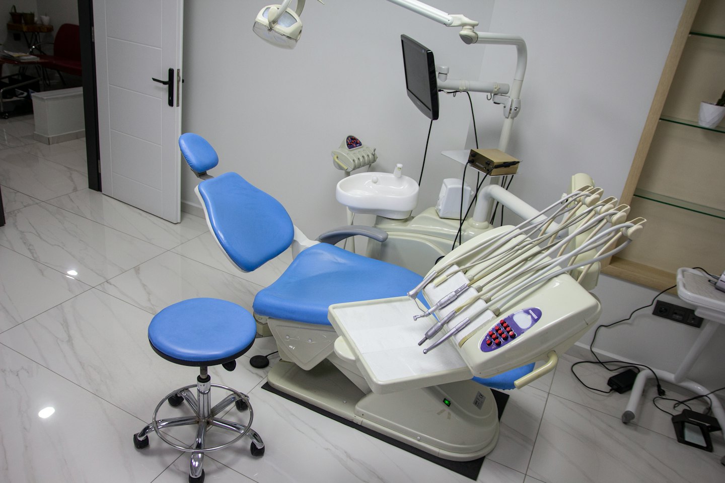 Consultorio dental vacío con silla y equipo azules.