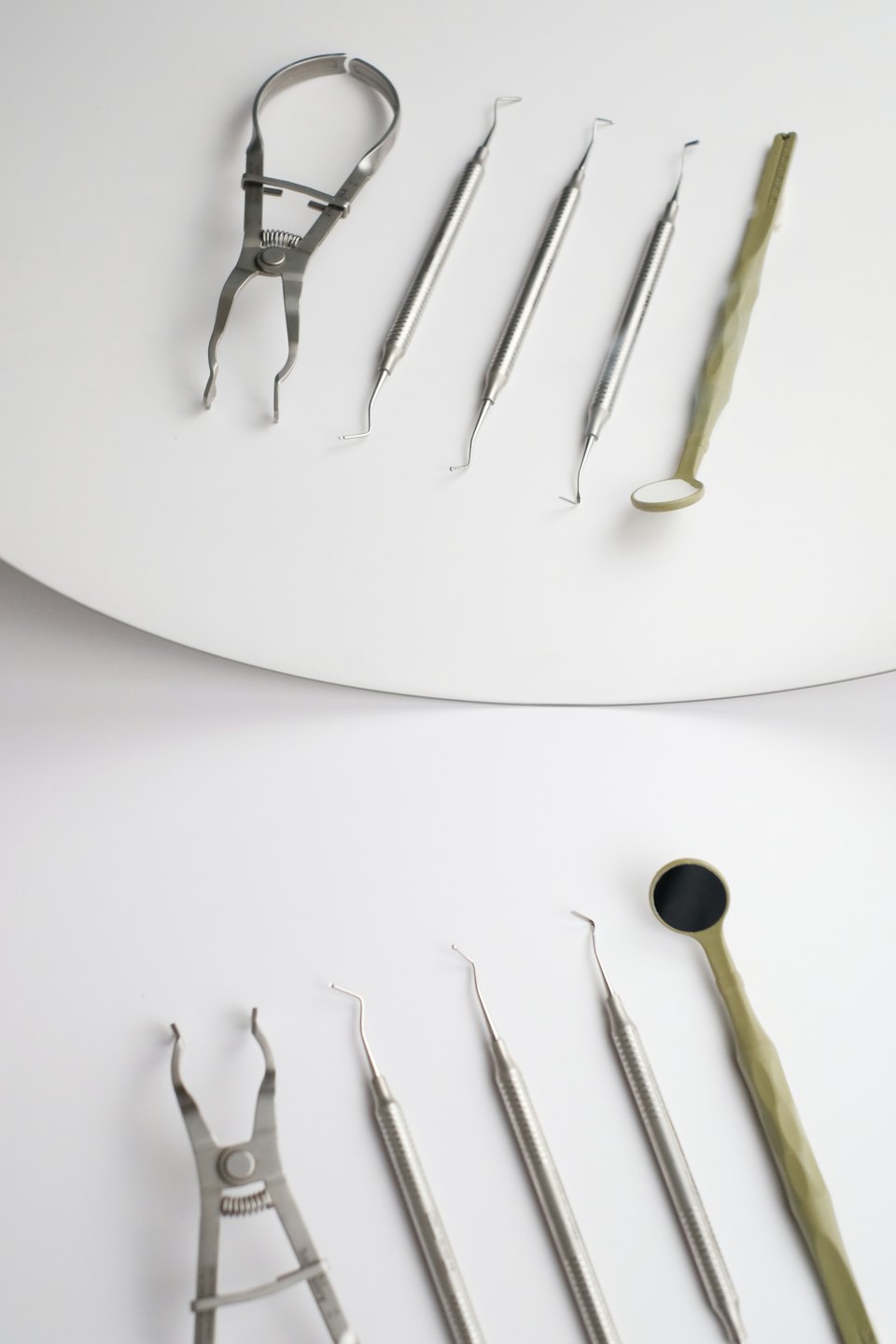 Instrumentos dentales brillantes dispuestos sobre una superficie blanca.